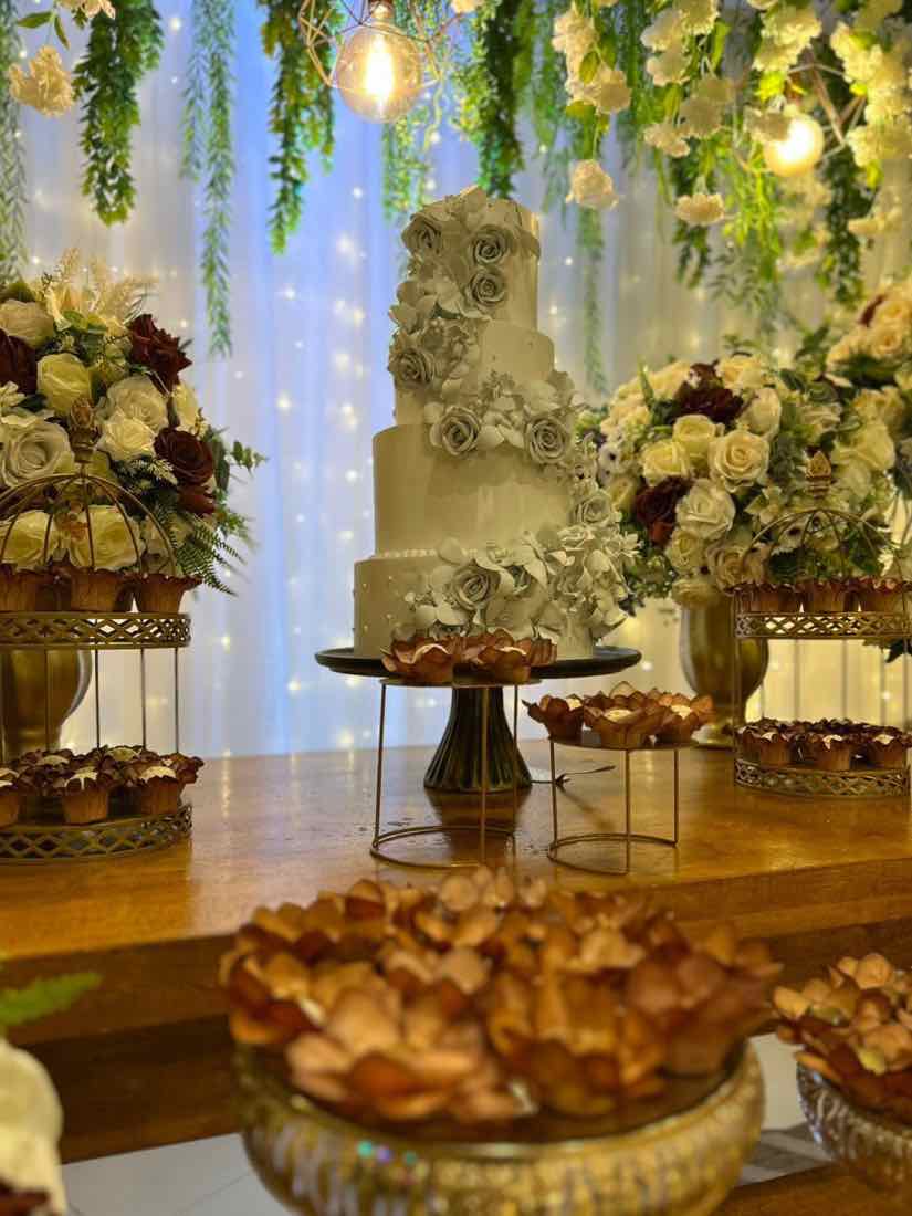 Bolo verde-oliva com rosas de acucar e doces na mesa de festa