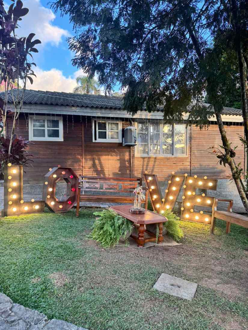 Letreiro LOVE iluminado no jardim com bancos de madeira