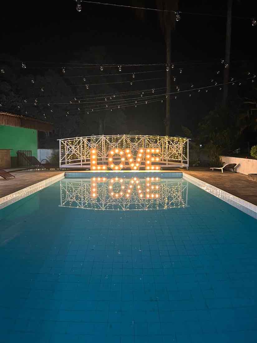 Piscina iluminada à noite com letreiro LOVE