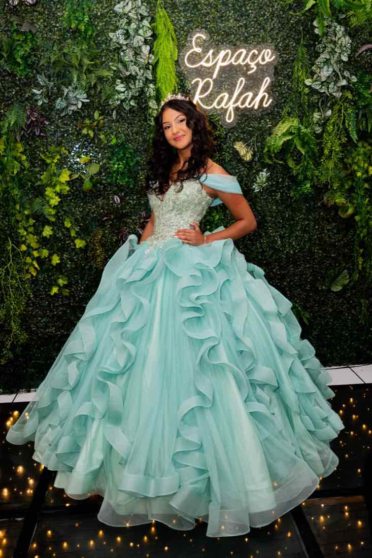 Debutante de vestido verde-água diante do neon Espaço Rafah